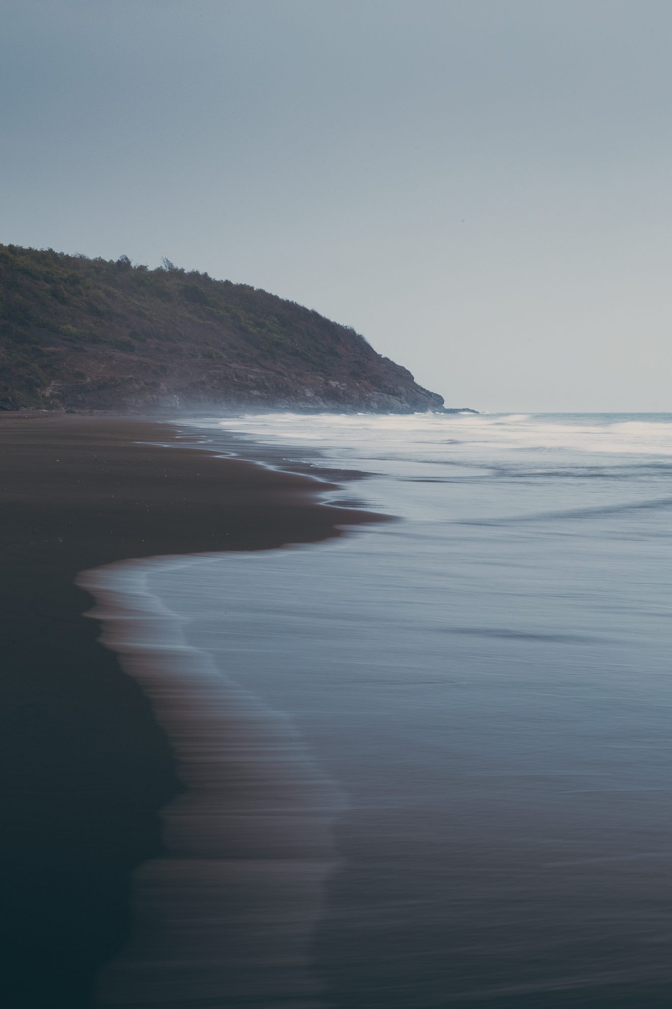 Long exposure of a curving beach at dusk