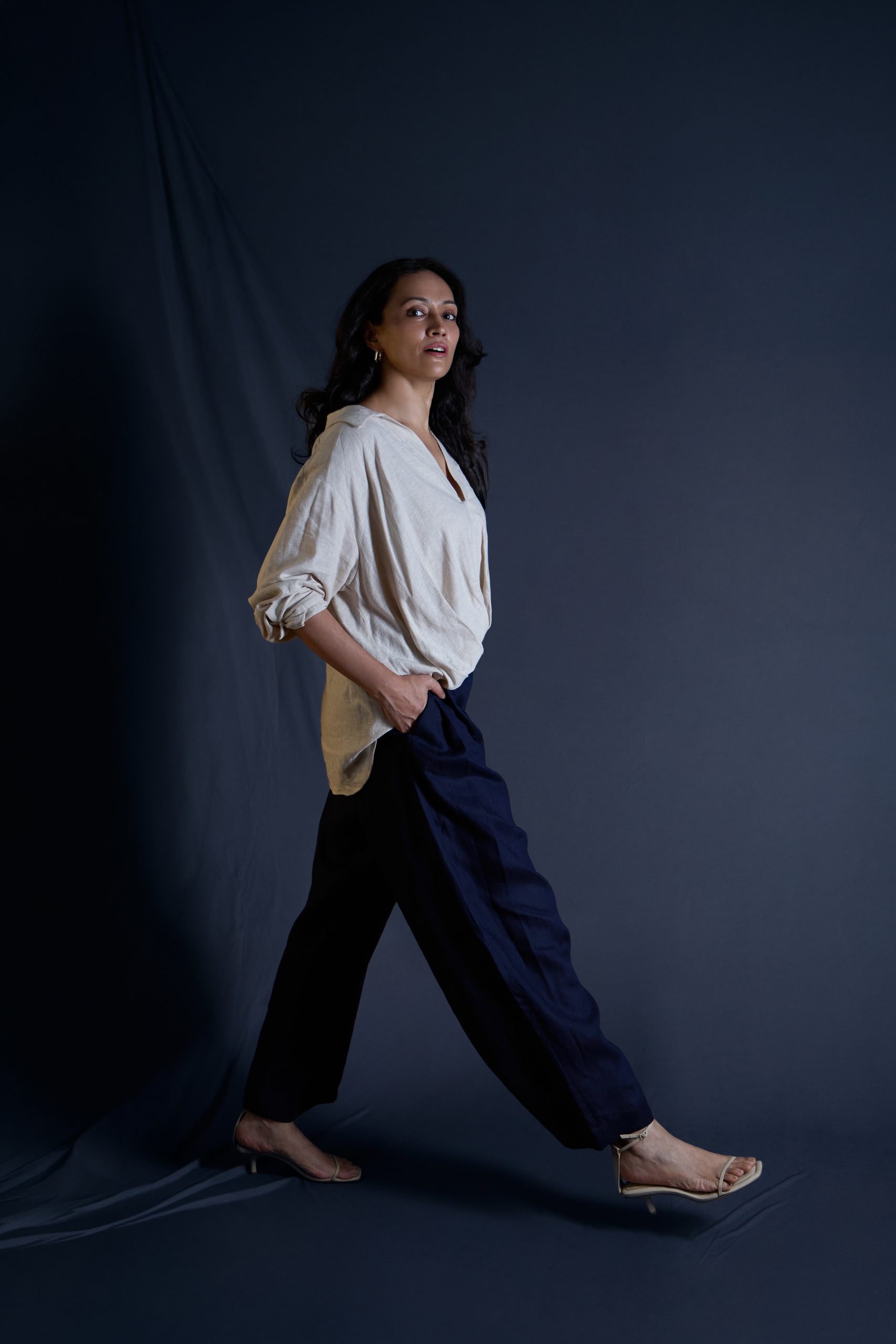 Model walking, white shirt and black trousers, navy backdrop